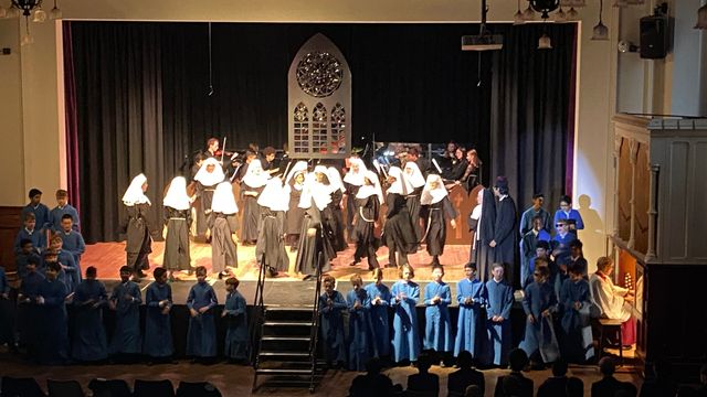 The nuns' choir on stage under the stained glass window